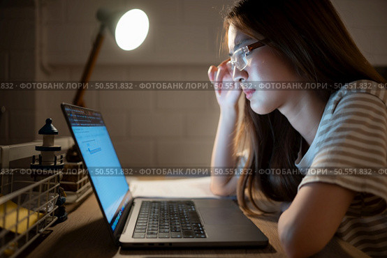A young woman works on her laptop at home. It is characterized with headaches that occur when stressed. Стоковое фото, агентство Ingram Publishing / Фотобанк Лори