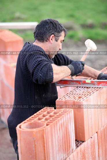 Adjusting wall with wooden mallet. Стоковое фото, агентство Ingram Publishing / Фотобанк Лори