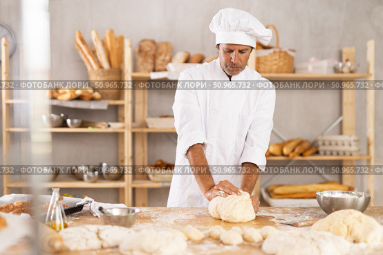 Adult male baker kneading dough on table. Стоковое фото, фотограф Яков Филимонов / Фотобанк Лори