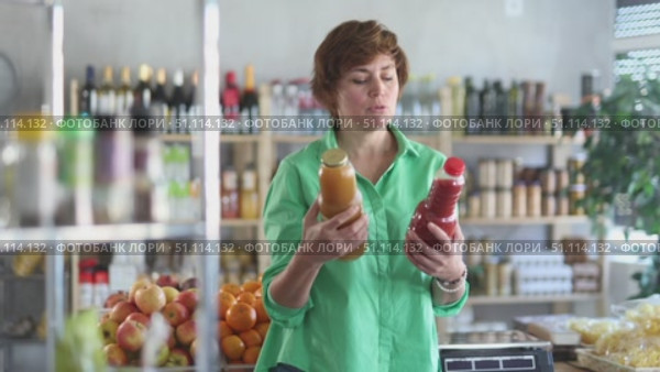 Adult woman chooses peach and tomato juices. Стоковое видео, видеограф Яков Филимонов / Фотобанк Лори