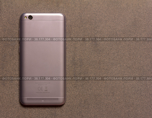 Adygea, Russia - January 3, 2018: Chinese smartphone Xiaomi Redmi 5A silver back side close up view from above on grey background with copy space. Редакционное фото, фотограф Андрей С / Фотобанк Лори