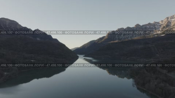 Aerial - Serene mountain lake reflecting golden sunset sky, crystal clear waters mirroring rugged Spanish Pyrenees wilderness with tranquil landscape glowing. Стоковое видео, видеограф Данил Руденко / Фотобанк Лори