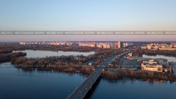 Aerial top view of Kiev skyline on the sunset. Dnieper river with bridge, Shopping center Skymol, parking and Truhaniv island from above, Ukraine Photo from the drone. Dnieper river with bridge, Shopping center Skymol, parking and Truhaniv island from above in Kyiv, Ukraine. Стоковое фото, агентство Ingram Publishing / Фотобанк Лори