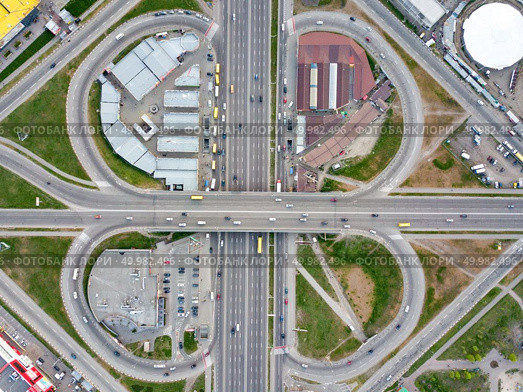 Aerial view district Poznyaki, road junction with passing cars, parking, green area and buildings in sity Kiev, Ukraine. Photo from the drone. Aerial view road junction, in the form of a quatrefoil Poznyaki district, Kiev. Стоковое фото, агентство Ingram Publishing / Фотобанк Лори