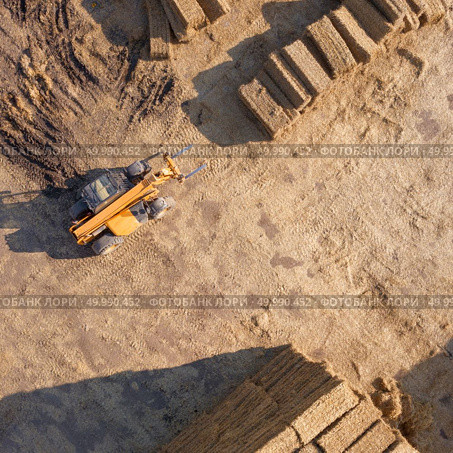 Aerial view from drone large stacks of dry hay bales in the field. Tractor folds bales of hay on a sunny day. Autumn harvest. Top view. Aerial view agricultural machinery tractor stacks bales of hay in the field. Photo from drone. Top view. Стоковое фото, агентство Ingram Publishing / Фотобанк Лори