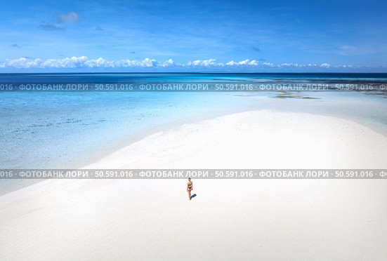 Aerial view of alone young woman on the sandbank in ocean, white sand, blue sea during low tide at sunny summer day in Nakupenda, Zanzibar island. Top view of girl, sand spit, water, sky with clouds. Стоковое фото, агентство Ingram Publishing / Фотобанк Лори