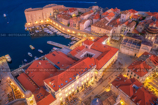 Aerial view of boats and yachts and beautiful architecture at night in Dubrovnik, Croatia. Top view of old city at sunset. Port in the sea, city lights, historical centre, buildings and red roofs. Стоковое фото, агентство Ingram Publishing / Фотобанк Лори
