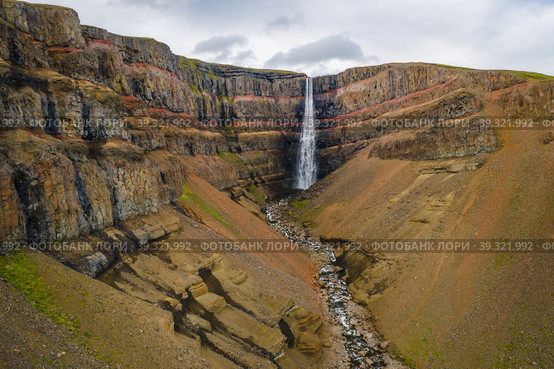 Aerial view of Hengifoss waterfall in East Iceland. Hengifoss is the third highest waterfall in Iceland and is surrounded by basaltic strata with red layers of clay between the basaltic layers (2020 год). Стоковое фото, фотограф Igor Tichonow / Фотобанк Лори