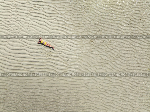 Aerial view of lying sporty slim woman, clear water and sandy beach in low tide at sunrise in summer in Zanzibar island. Top drone view of beautiful girl, sandbank, sea, clear water. Tropical. Travel. Стоковое фото, агентство Ingram Publishing / Фотобанк Лори