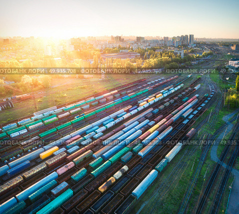 Aerial view of multicolored freight trains. Cargo wagons on railway station. Wagons with goods on railroad. Heavy industry. Industrial landscape with train, railway platfform at sunset. Top view.Depot. Aerial view of colorful freight trains on railroad. Стоковое фото, агентство Ingram Publishing / Фотобанк Лори