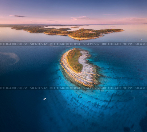Aerial view of small island, Kamenjak cape, Adriatic sea, Croatia at sunset in summer. Beautiful landscape with sea coast, mountains, clear water, purple sky at twilight. Top view from drone. Panorama. Aerial view of small island, Kamenjak cape, Adriatic sea, Croatia. Стоковое фото, агентство Ingram Publishing / Фотобанк Лори