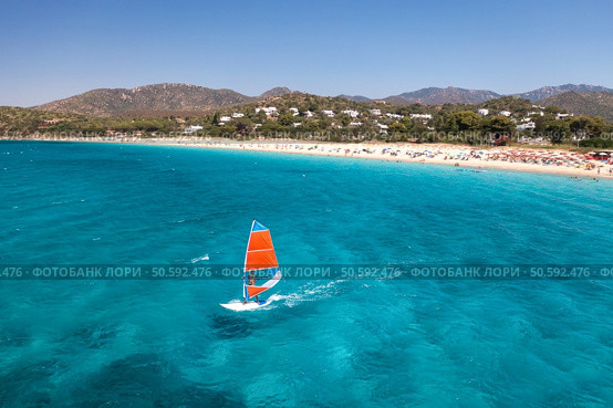 Aerial view of windsurfer on blue sea at sunny summer day. Windsurfing. Extreme sport and vacation. Top view of man on windsurfer board, waves, clear azure water in Sardinia, Italy. Tropical landscape. Стоковое фото, агентство Ingram Publishing / Фотобанк Лори