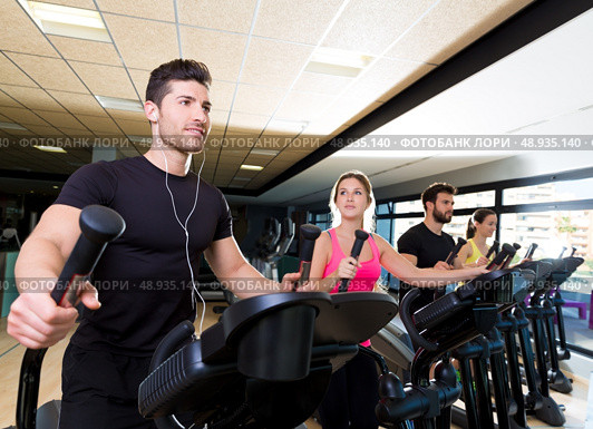 Aerobics elliptical walker trainer group at fitness gym workout. Стоковое фото, агентство Ingram Publishing / Фотобанк Лори