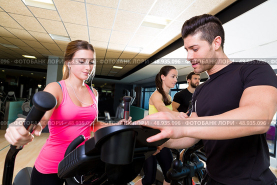 Aerobics elliptical walker trainer personal trainer man at fitness gym workout. Стоковое фото, агентство Ingram Publishing / Фотобанк Лори