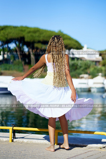 African girl walking along a seaport wearing a nice summer dress.. African woman walking along a seaport wearing a nice summer dress. Стоковое фото, агентство Ingram Publishing / Фотобанк Лори