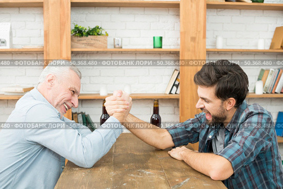 aged man young guy with hands clasped arm wrestling challenge table room. Стоковое фото, агентство Ingram Publishing / Фотобанк Лори