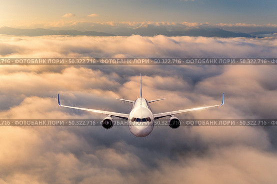Airplane is flying above the clouds at sunrise in summer. Landscape with passenger airplane, beautiful clouds, mountains, sky. Aircraft is taking off. Business travel. Commercial plane. Aerial view . Стоковое фото, агентство Ingram Publishing / Фотобанк Лори
