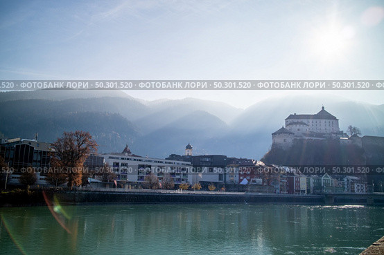 Amazing autumn landscape with Kufstein Fortress and traditional houses on a boardwalk of smooth Inn river on a forefront on a background of clear sunny sky, Kufstein Austria.. Kufstein Fortress beautiful landscape with smooth river on a forefront, Austria. Стоковое фото, агентство Ingram Publishing / Фотобанк Лори