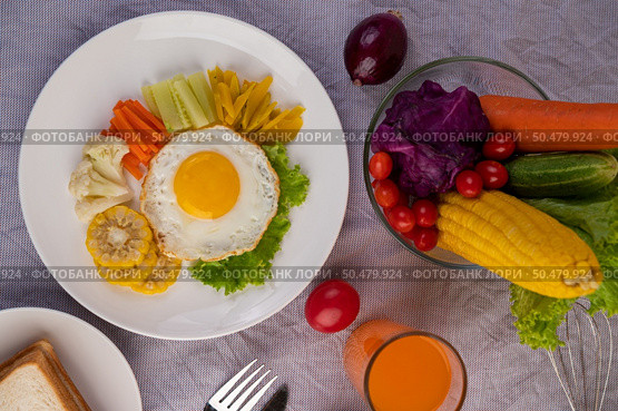 American breakfast on a white background with fried egg, salad, pumpkin, cucumber, carrot, corn, cauliflower, tomato, toast and orange juice. Стоковое фото, агентство Ingram Publishing / Фотобанк Лори