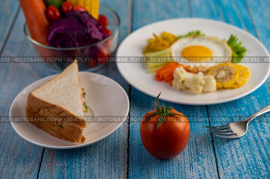 American breakfast on a white background with fried egg, salad, pumpkin, cucumber, carrot, corn, cauliflower, tomato and sandwich . Стоковое фото, агентство Ingram Publishing / Фотобанк Лори