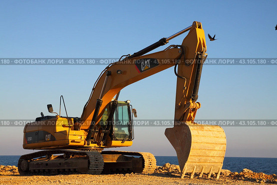 Американский экскаватор Caterpillar на закате. Строительная техника на берегу моря. (2012 год). Редакционное фото, фотограф Дорощенко Элла / Фотобанк Лори