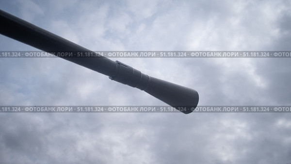 Amidst a war-torn landscape in Russia, a cannon ominously faces a dramatic cloudy sky, hinting at impending action. Smoke and fire threaten the quiet atmosphere, illustrating conflict. Стоковое фото, фотограф Громов Александр / Фотобанк Лори