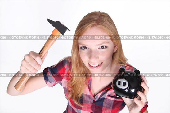 Amusing shot of young girl trying to break open her piggy bank with a hammer. Стоковое фото, агентство Ingram Publishing / Фотобанк Лори