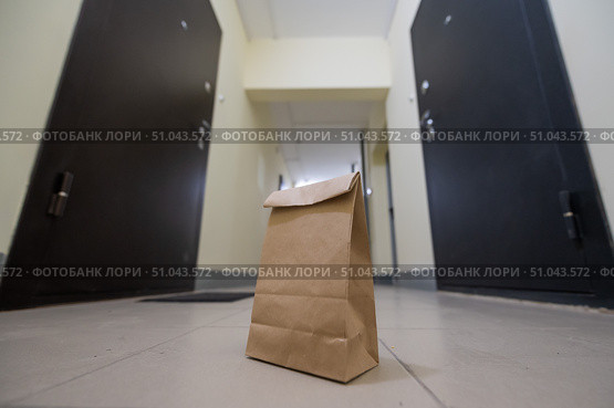 An eco paper bag is standing in the lobby on the doorstep of the apartment. Contactless food delivery to the epidemic. The courier left an online order at the entrance. precautionary measures. Стоковое фото, фотограф Михаил Решетников / Фотобанк Лори