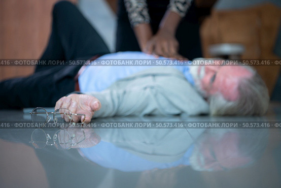 An elderly businessman suffered a sudden heart failure at work, A coworker was administering CPR to offer basic life support. Стоковое фото, агентство Ingram Publishing / Фотобанк Лори