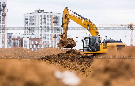An excavator on a construction site in close-up. An excavator digs the ground with a bucket for construction. Heavy machinery for construction and landscaping. Стоковое фото, фотограф Photojuli / Фотобанк Лори