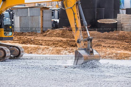 An excavator on a construction site in close-up. The excavator rams the crushed stone with a bucket for construction. Heavy machinery for construction and landscaping. Стоковое фото, фотограф Photojuli / Фотобанк Лори
