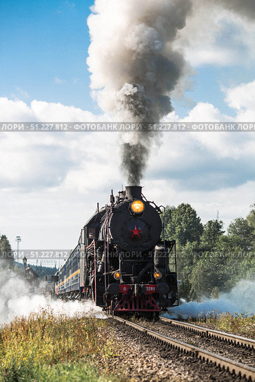 An old Soviet steam locomotive of the L series. The Ruskeala Express retro train is on its way to the mountain park. Thick smoke is coming from the chimney. Russia, Republic of Karelia, Sortavala, August 10, 2025. Редакционное фото, фотограф Photojuli / Фотобанк Лори