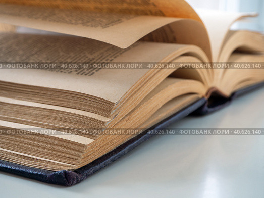 An old thick book is open and lies on the table. The book is located diagonally. Pages turned yellow from old age. Стоковое фото, фотограф Бузмакова Светлана / Фотобанк Лори