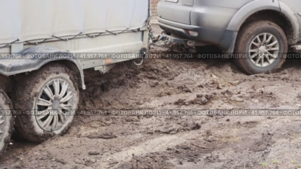 An SUV with a cargo trailer slides through the mud, trying to get out. Seasonal bad weather in rural areas. (2023 год). Редакционное видео, видеограф Коханова Наталья / Фотобанк Лори