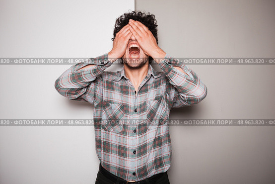 An upset young man is standing against a green and white background. Стоковое фото, агентство Ingram Publishing / Фотобанк Лори