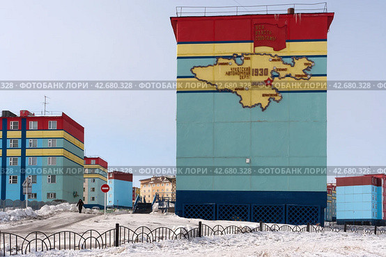 Анадырь, Чукотка, Россия. Красочные здания в северном городе. На стене карта Чукотского автономного округа. На флаге надпись на русском языке «ВСЯ ВЛАСТЬ СОВЕТАМ!». Редакционное фото, фотограф Андрей Степанов / Фотобанк Лори
