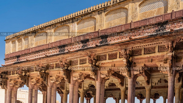Ancient Indian architecture. The colonnade of the open hall is built of sandstone. Columns with carved capitals, arches, ornaments, patterns, lattices are visible. Blue sky. Amber Fort. Jaipur (2022 год). Стоковое фото, фотограф Вера Ивановна Кубарева / Фотобанк Лори