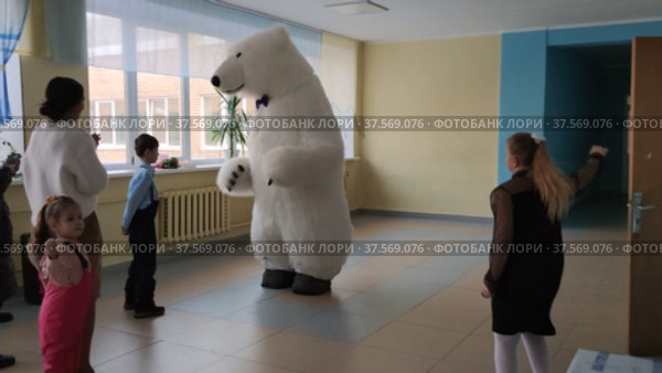 Аниматор в костюме белого медведя танцует с детьми в школе на новогоднем празднике. An animator in a polar bear costume dances with children at school on a New Year's holiday. Редакционное видео, видеограф Мария / Фотобанк Лори