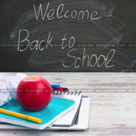 Apple with school supplies on white aged wooden table, blackboard and welcome back to school in background. Apple with school supplies. Стоковое фото, агентство Ingram Publishing / Фотобанк Лори