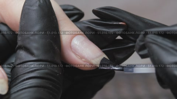 Applying a clear liquid to the nail plate of a finger with a black brush from a jar of nail polish. Nail treatment and restoration. Стоковое видео, видеограф Константин Мерцалов / Фотобанк Лори