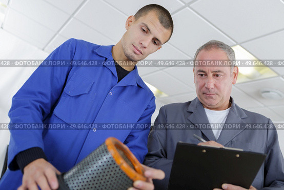 apprentice and mentor replacing of motor filter at garage. Стоковое фото, агентство Ingram Publishing / Фотобанк Лори