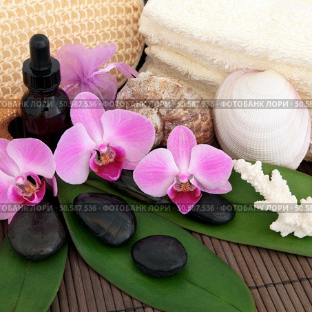 Aromatherapy treatment with spa stones, essential oil, pink orchid flowers, exfoliating scrub, towels and shells over bamboo background. Стоковое фото, агентство Ingram Publishing / Фотобанк Лори