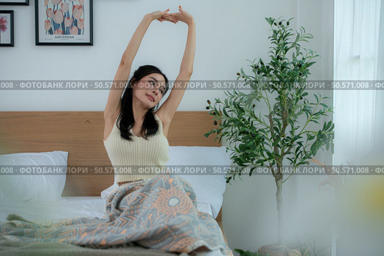 Asian woman feels well after waking up in the morning on a work day. Стоковое фото, агентство Ingram Publishing / Фотобанк Лори