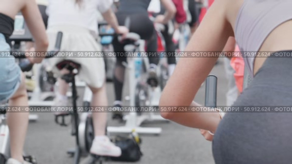 Athletes pedaling on exercise bikes during sports day. Стоковое видео, видеограф Mikhail Davidovich / Фотобанк Лори