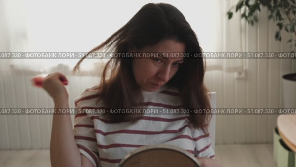 Attractive brunette mid adult woman putting on makeup looking in the mirror. Beautiful lady caring her face. 40 years old female applied cosmetics. Natural beauty and aging concept. Skin care, make-up. Стоковое видео, видеограф Марина Демидюк / Фотобанк Лори