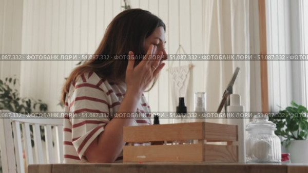 Attractive brunette mid adult woman putting on makeup looking in the mirror. Beautiful lady caring her face. 40 years old female applied cosmetics. Natural beauty and aging concept. Skin care, make-up. Стоковое видео, видеограф Марина Демидюк / Фотобанк Лори
