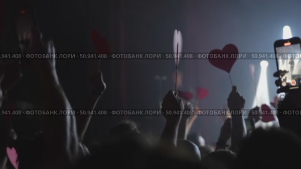 Audience holding heart-shaped signs during a live concert performance with dramatic lighting effects. Стоковое видео, видеограф Данил Руденко / Фотобанк Лори