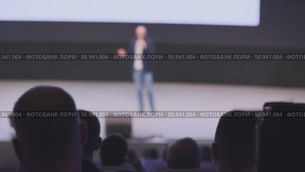 Audience observing a speaker presenting on stage in a conference setting. Стоковое видео, видеограф Антон Гвоздиков / Фотобанк Лори