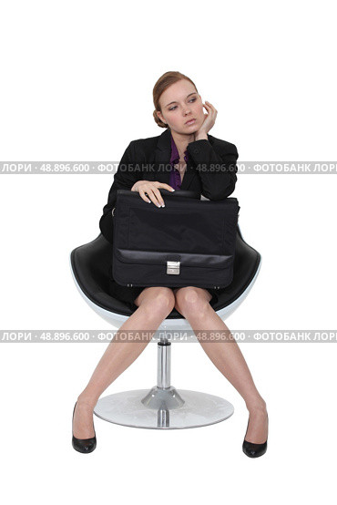 Austere businesswoman sitting in a chair with a briefcase on her lap. Стоковое фото, агентство Ingram Publishing / Фотобанк Лори