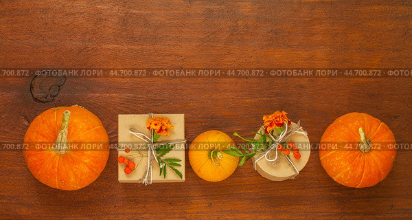 Autumn composition with pumpkins, marigolds and handmade gifts in paper gift boxes on old wooden background. Congratulations on autumn holiday, Thanksgiving, Halloween or beginning of autumn. Стоковое фото, фотограф Виктория Катьянова / Фотобанк Лори